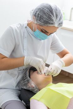 Dentist installing a patient cheek retractor in dentist office