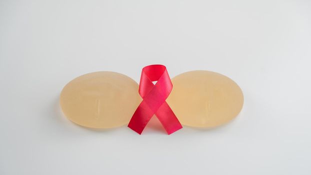 Breast implants and satin ribbon. Breast cancer awareness symbol.