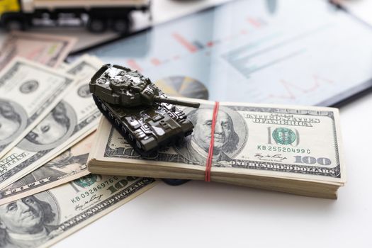 toy tank on the background of dollar bills
