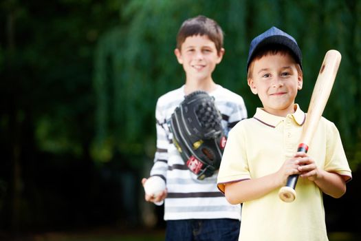 Im gonna hit a home run. Two young boys smiling happily after an energetic game of baseball in the park - Copyspace.