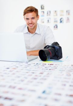 Smart photographer using laptop. Portrait of smart male photographer using laptop and smiling.