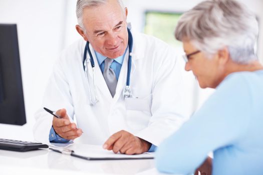 Doctor discussing medical report with mature patient. Smiling male doctor discussing medical report with mature female.