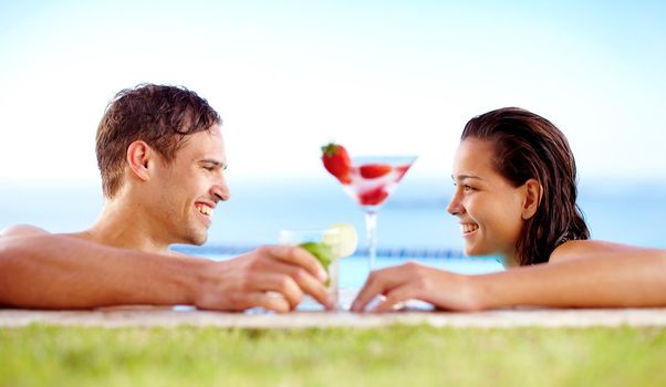 Sharing a summery afternoon. Gorgeous couple enjoying drinks in the pool.
