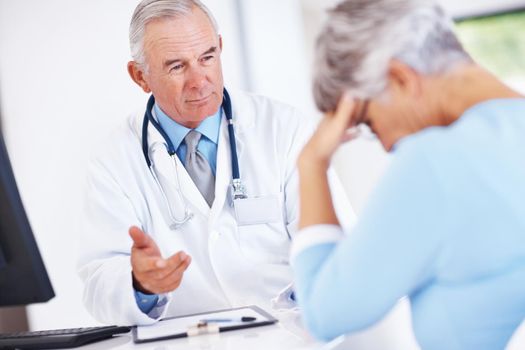 Doctor discussing reports with unhappy patient. Focus on mature doctor discussing medical report with unhappy patient.