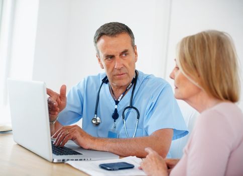 Medical doctor discussing with female patient using laptop. Portrait of a medical doctor discussing with female patient using laptop at clinic.