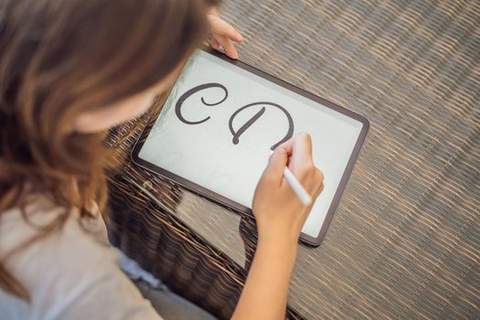 Calligrapher Young Woman writes phrase on digital tablet. Inscribing ornamental decorated letters. Calligraphy, graphic design, lettering, handwriting, creation