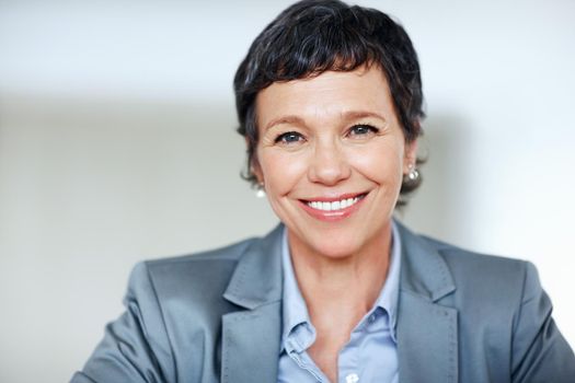 Female executive smiling. Portrait of successful mature female executive smiling over plain background.