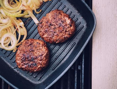Cooking minced beef burger on cast iron grill skillet outdoors, red meat on frying pan, grilling food in the garden, English countryside living