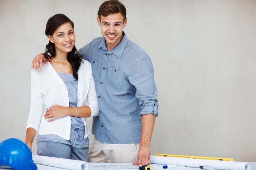 Attractive couple smiling with blueprint. Portrait of attractive young couple smiling while going through house plan.