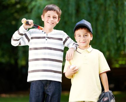 The Baseball Brothers. Two young boys smiling happily after an energetic game of baseball in the park.