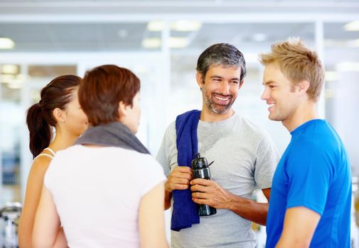 Group of friends at the gym. Mature man conversing with friends after workout at gym.
