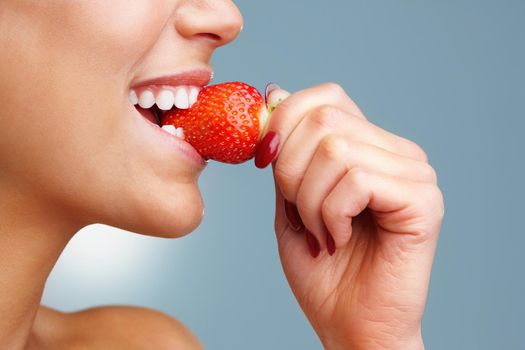 Macro view of a pretty young female eating fresh strawberry. Macro view of a pretty young woman eating fresh strawberry.