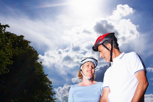 Loving couple wearing protective helmet against cloudy sky. Portrait of a loving couple wearing protective helmet against cloudy sky.