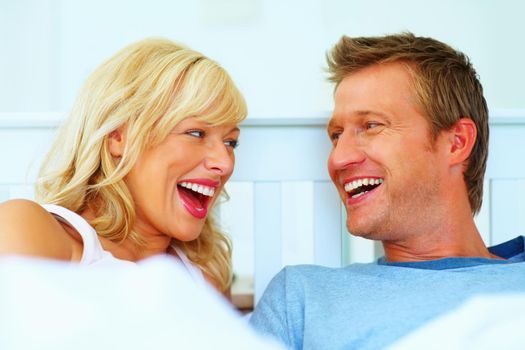 Cheerful middle aged couple laughing while looking at each other. Portrait of a cheerful middle aged couple laughing while looking at each other.