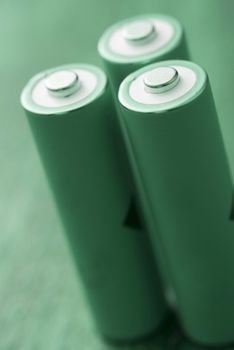Three standing green batteries on plain background
