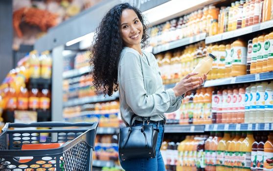 Portrait of a woman with juice while shopping in a grocery store with a retail product sale. Happy customer with a wellness, health and diet lifestyle buying healthy groceries at a supermarket.