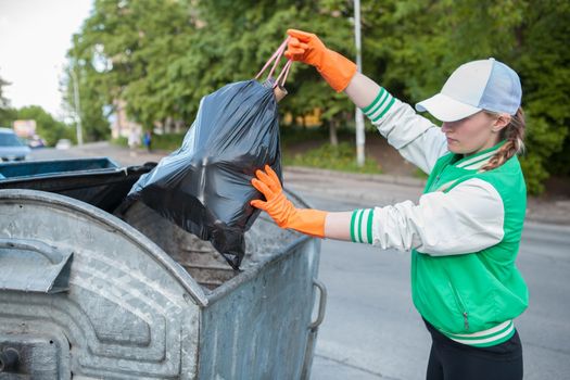 Volunteer putting trash bag into the trash can outdoors