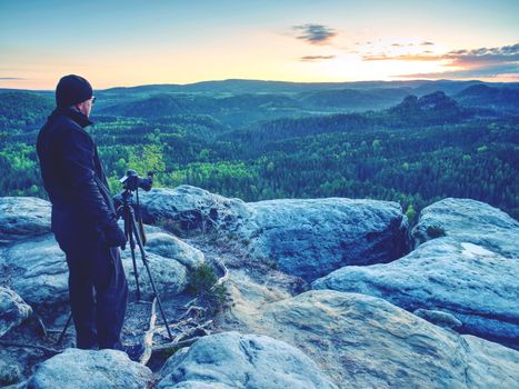 Photographer on mountain cliff take picture of landscape awaking.