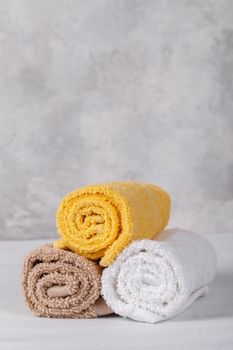 Spa composition with white, pink and brown soft rolled cotton towels, copy space