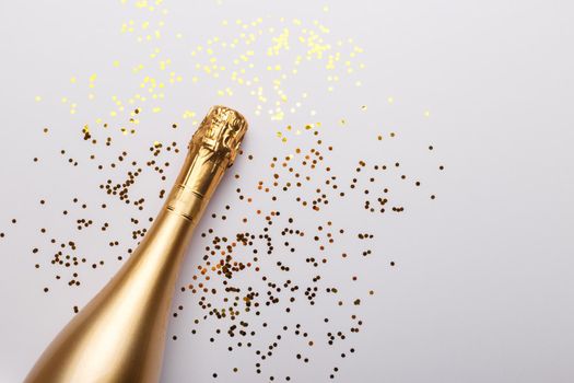 Flat lay composition of Champagne bottle and confetti