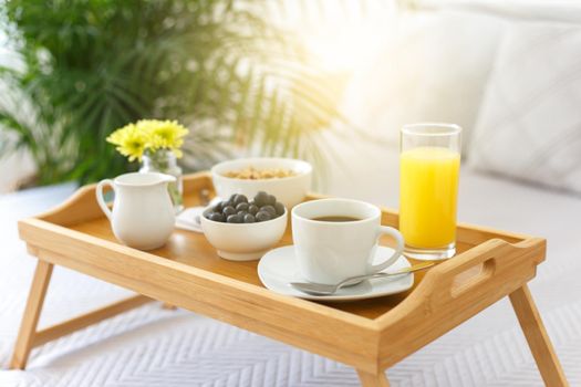 Wooden tray with breakfast on the bed 