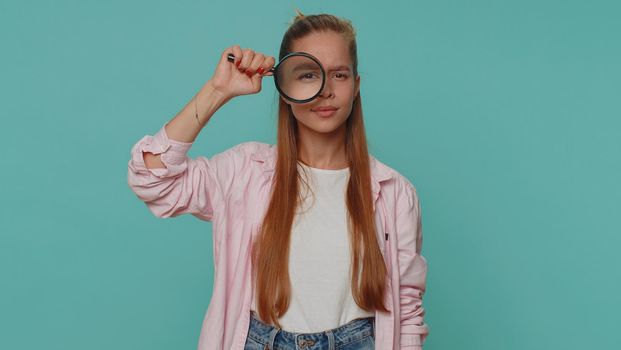 Researcher scientist girl holding magnifying glass near face, looking to camera with big zoomed eye