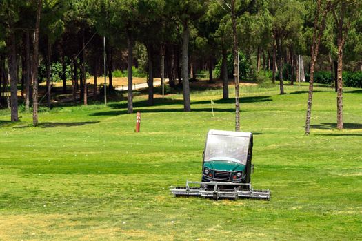 Golf course and golf cart collecting golf balls. Ballpicker on driving range of golf club