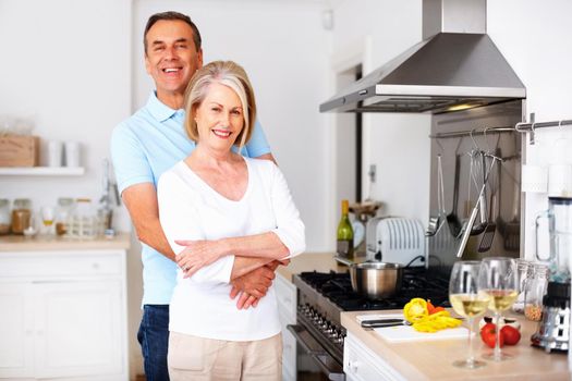 Loving mature man embracing wife from behind at kitchen. Portrait of a loving mature man embracing wife from behind at kitchen.