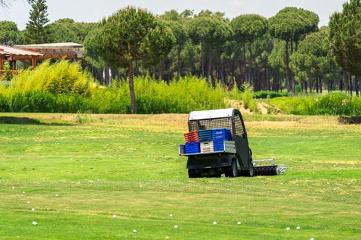 Golf course and golf cart collecting golf balls. Ballpicker on driving range of golf club