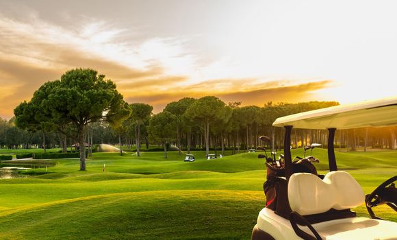 Golf cart on beautiful golf course at sunset