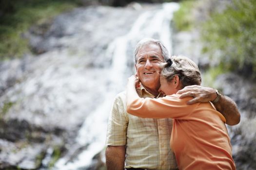 Sharing wonderful times together. An affectionate senior couple standing against the backdrop of a picturesque waterfall.