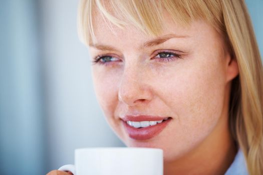 Beautiful young girl with coffee cup. Closeup of pretty woman day dreaming while holding a coffee cup.