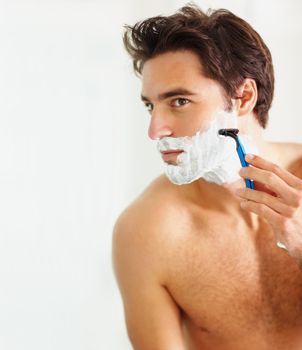 Smart young guy using a razor to shave. Portrait of a young handsome guy shaving with copyspace.