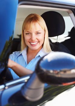 Pretty female smiling from the front seat of a car. Portrait of a smiling young woman sitting in the front seat of a car.