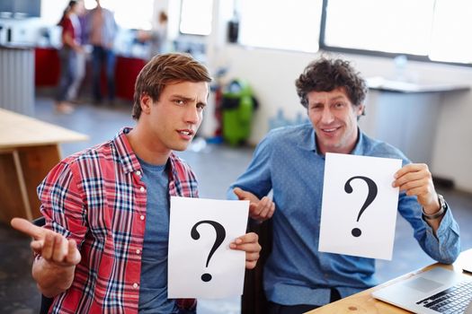 Business is full of questions. Portrait of two coworkers looking confused while holding question mark signs.