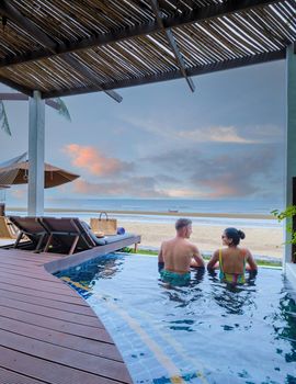 Couple in luxury villa enjoying in the plunge pool looking out over ocean and beach during sunset