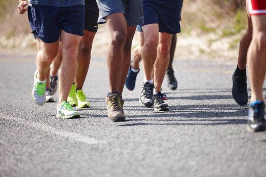 No pain, no gain. Work those legs. the legs of a group of men running a road race.