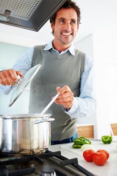 Mature man looking away while cooking in kitchen. Portrait of a happy mature man looking away while cooking in kitchen.
