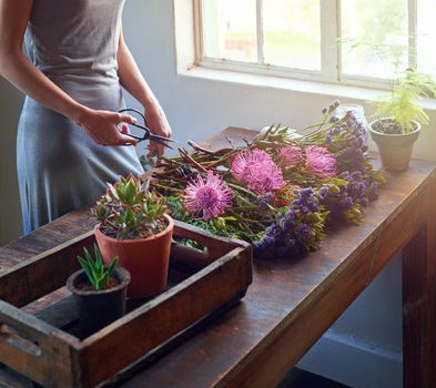 Bringing nature indoors. a pretty floral bouquet being completed on a wooden counter top.