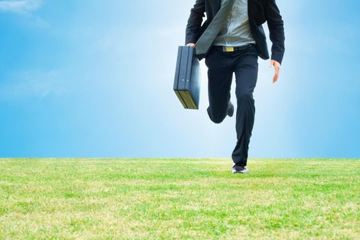 Business man running with a briefcase on a field. Cropped image of a business man running with a briefcase on a field - Copyspace.