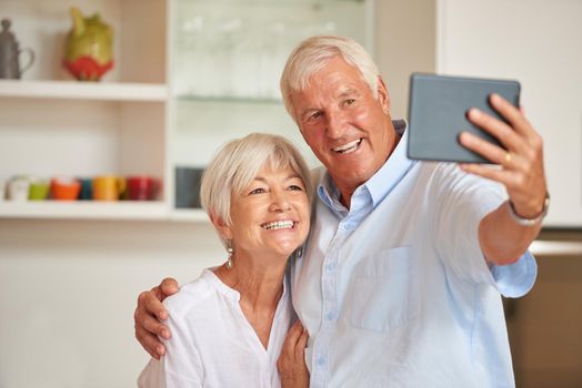 Loving this selfie thing. a senior couple taking a selfie with their tablet.