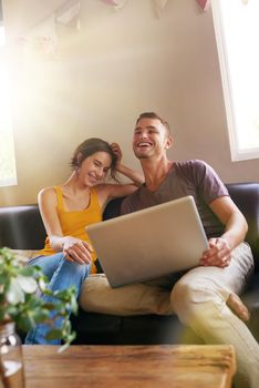 Thats the funniest video. a happy young couple using a laptop together on the sofa at home.