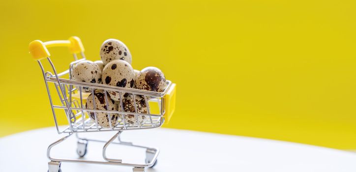 Happy Easter background. Easter quail eggs in the shopping cart on bright yellow paper. Festive concept