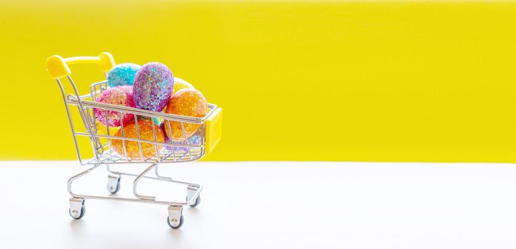 Happy Easter background. Easter multi-colored eggs in a basket on bright yellow paper. Festive concept