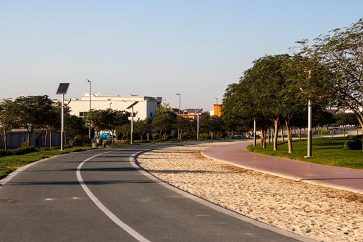 Jogging and cycling tracks in Al Warqa park, Dubai, UAE early in the morning. Lamp post powered by solar panels can be seen in the picture.
