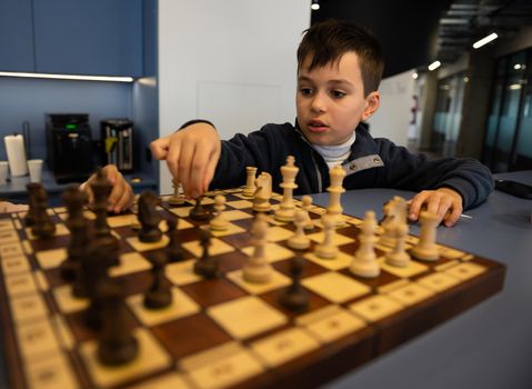 Concentrated Caucasian school boy developing chess strategy, playing board game
