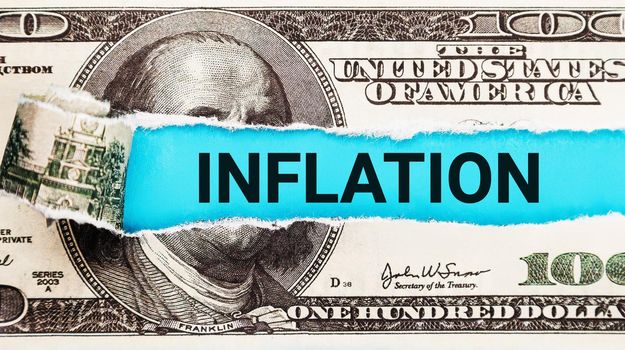 Inflation World economics and inflation control concept. Torn bills revealing Inflation words. Idea for FED consider interest rate hike, world economics and inflation control, US dollar inflation