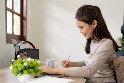 woman wearing using laptop in cafe, writing notes, attractive female student learning language, watching online webinar, listening audio course, e-learning education concept.