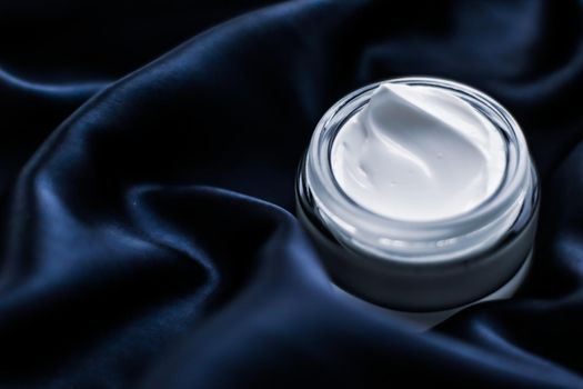 Luxury face cream jar on a dark blue silk