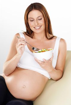 Making sure her pregnancy is a healthy and happy one. a pregnant woman eating a healthy salad.
